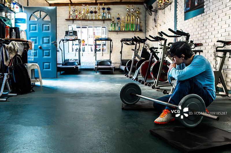 年轻男子在健身房进行力量训练，视力受限。图片素材