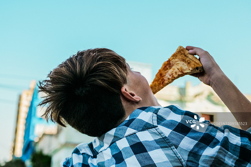 青少年男孩在户外吃披萨图片素材