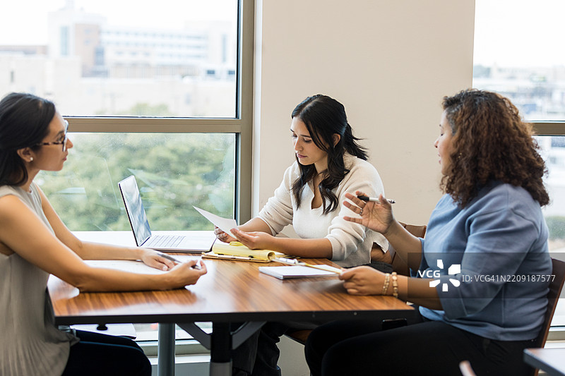 三位不同背景的女性在商务休闲装中讨论文件图片素材