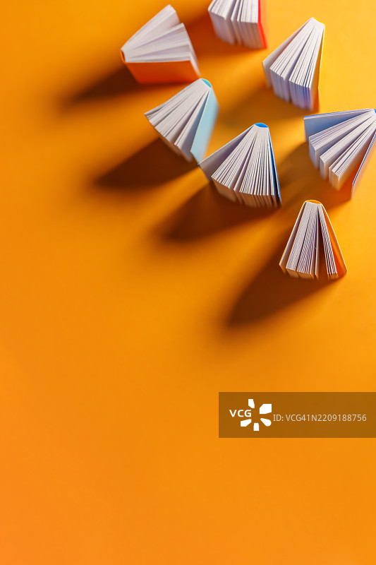 五颜六色的书本在橙色背景上扇形展开图片素材