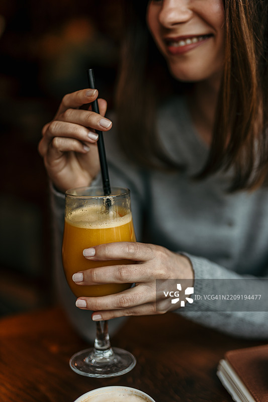 年轻女性在咖啡馆喝橙汁图片素材