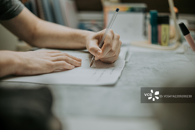 中景的西班牙裔男性学生在写作和学习图片素材