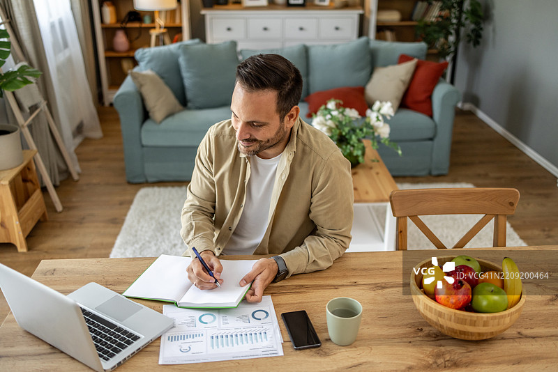 专注的企业家在家中用笔记本做笔记图片素材
