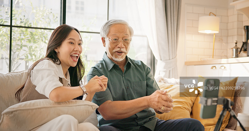 老爷爷和孙女使用智能手机直播舞蹈视频，分享至社交媒体。图片素材