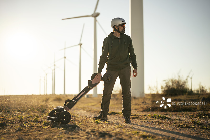 在风电场骑电动山地板的男子。可再生能源图片素材