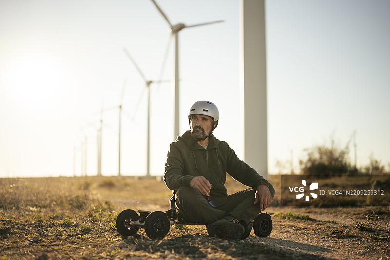 男子在风电场的电动山地板上放松。环保意识图片素材