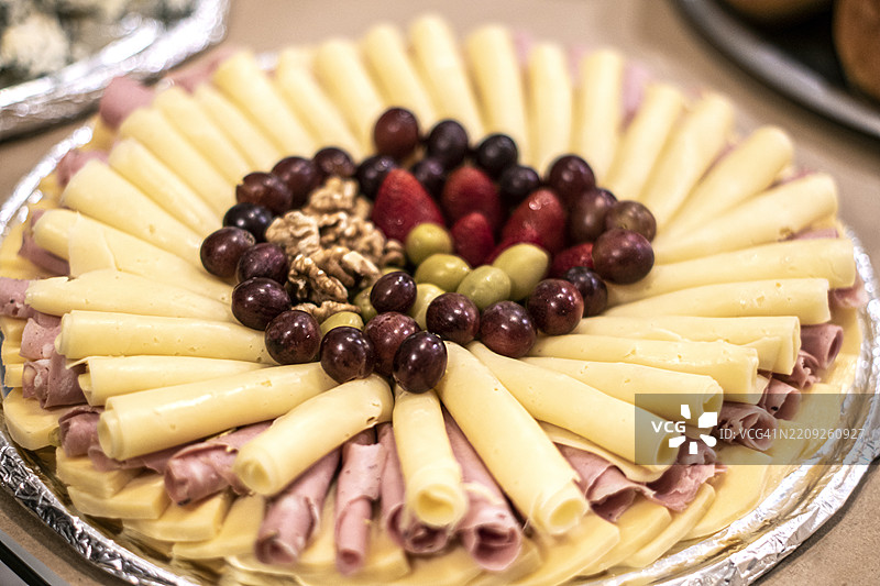奶酪、冷切肉、草莓、葡萄、橄榄和坚果的托盘。小吃。开胃菜。甜酸菜肴。图片素材