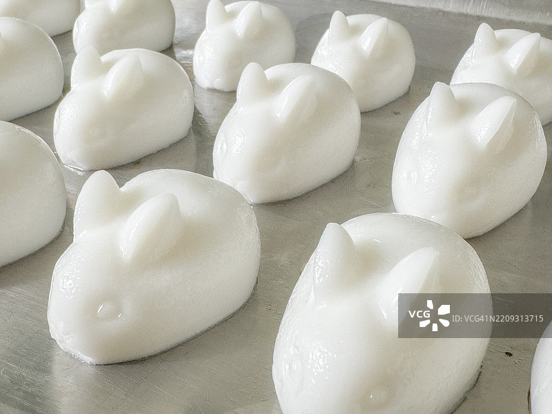 可爱的兔子形状椰子果冻 - 传统亚洲甜点。可爱的白色兔子形状椰子牛奶果冻。这些摇摇欲坠的美味展示了精致的工艺，兔耳朵栩栩如生，椰子味顺滑。图片素材