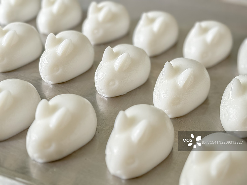 可爱的兔子形状椰子果冻 - 传统亚洲甜点。可爱的白色兔子形状椰子牛奶果冻。这些摇摇欲坠的美味展示了精致的工艺，兔耳朵栩栩如生，椰子味顺滑。图片素材