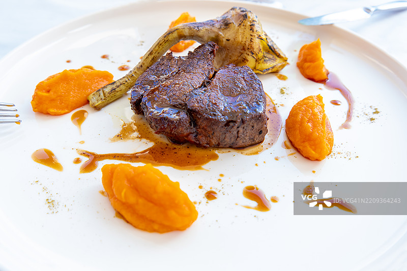 瑞士优质牛肉菲力配朝鲜蓟和美式土豆，摆放在白色盘子上图片素材