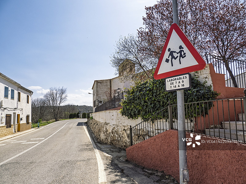一条穿过小镇的道路，路旁有警告儿童过马路的标志。图片素材