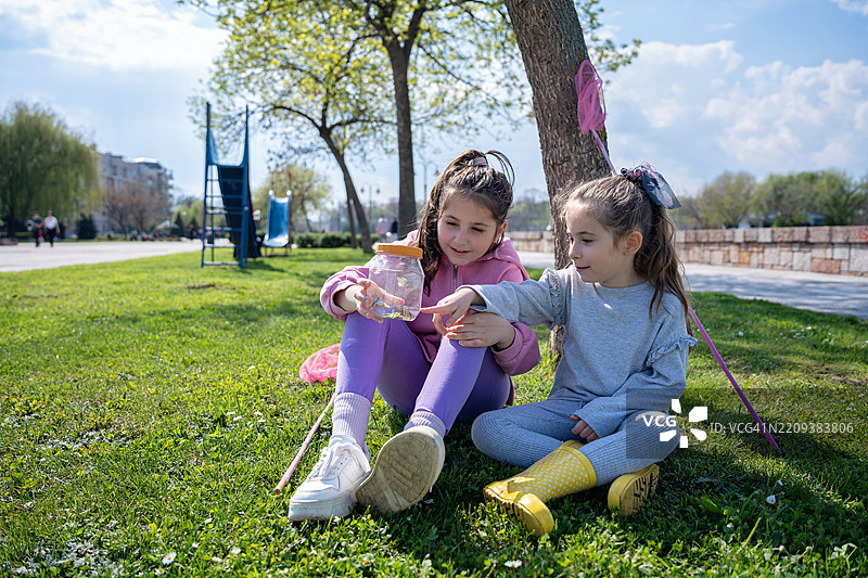两个年轻的姐妹在阳光明媚的公园里捕捉蝴蝶图片素材