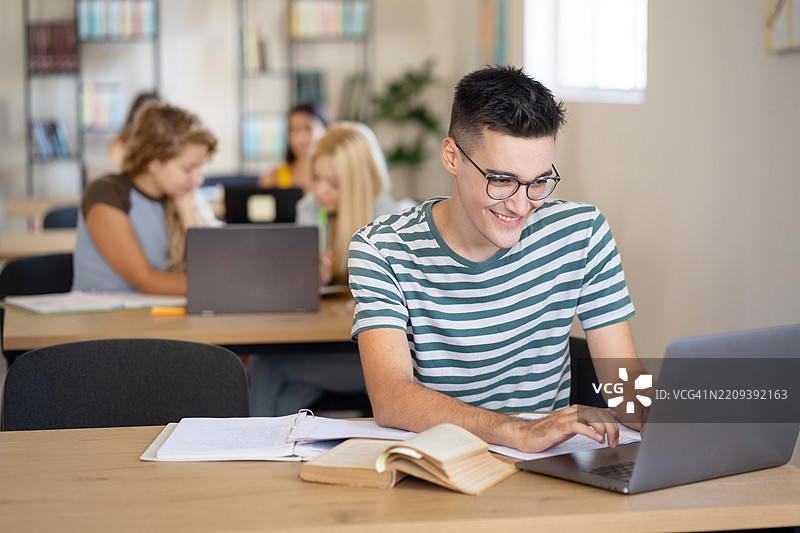 一位快乐的学生坐在图书馆里学习的肖像图片素材