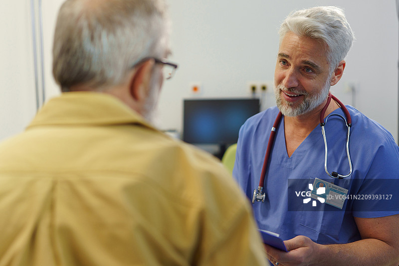 帅气的医生正在与年长患者咨询。图片素材