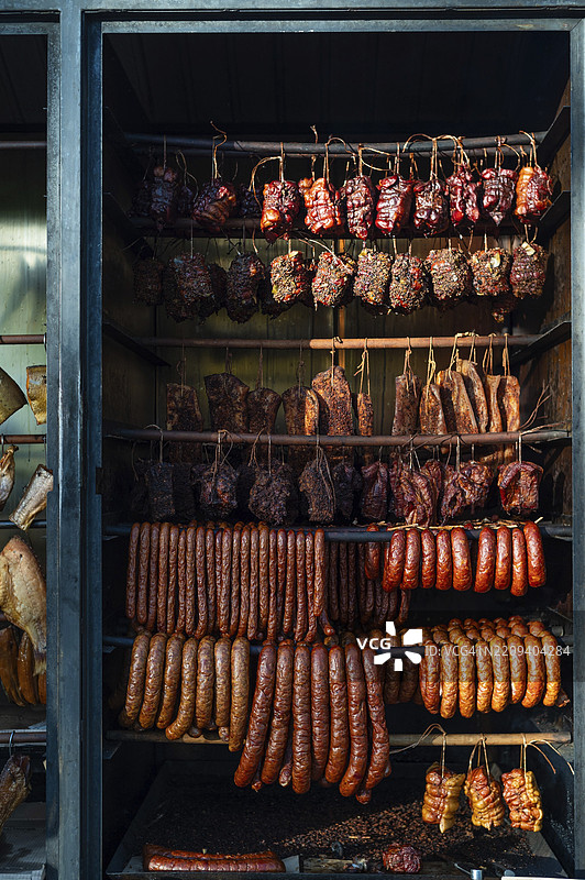 传统木柴烟熏房中悬挂的肉类和香肠图片素材