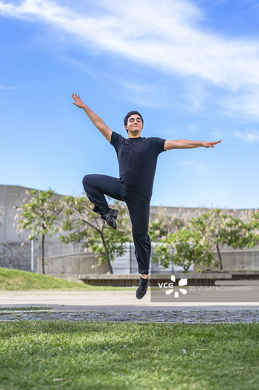 充满活力的年轻人在蓝天绿地的公园中欢快地跳跃图片素材
