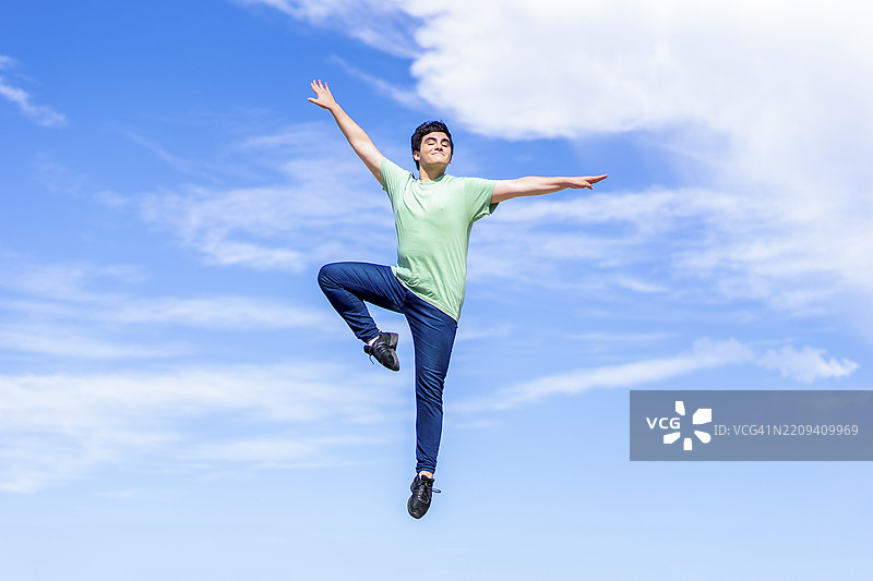 年轻男子在蓝天上快乐地跳跃图片素材