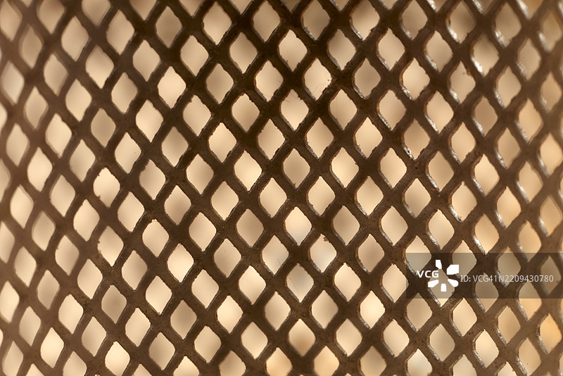 宏观摄影展示了扩展金属网的菱形图案，复杂的金属质感突显几何精度，背景柔和模糊。图片素材
