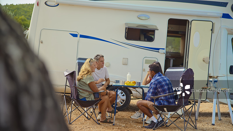 多元化的朋友们在风景如画的露营地海边享受户外早餐图片素材