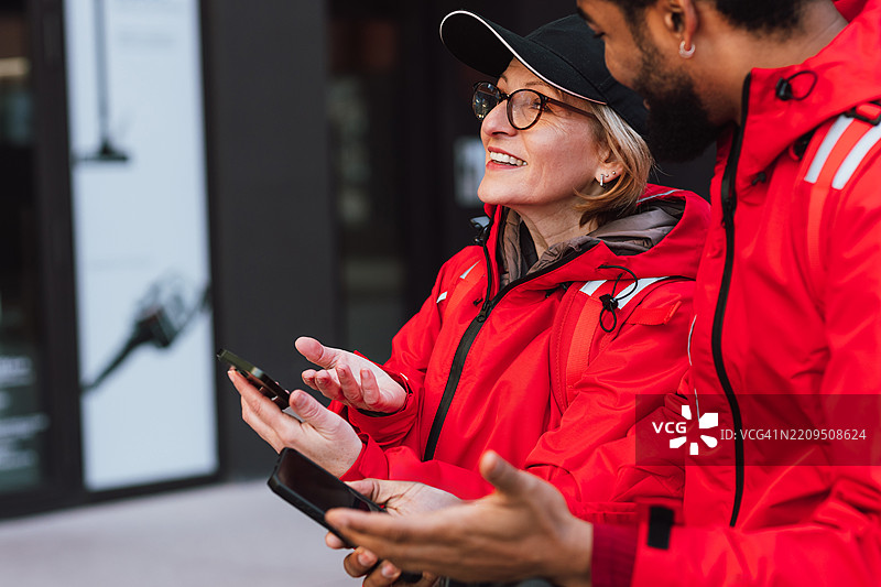 多元化的快递服务团队正在查看手机地图应用程序，规划送货路线。图片素材