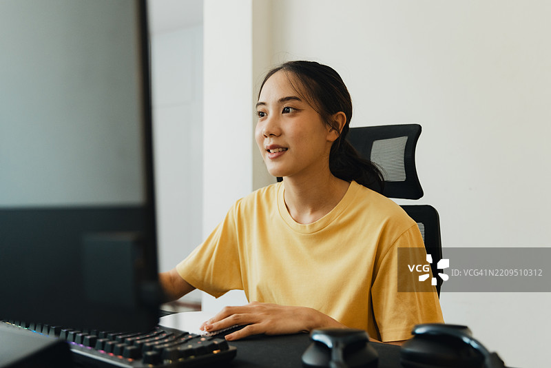年轻女性在明亮的环境中专注于现代工作空间的任务，桌上有电脑和配件。图片素材