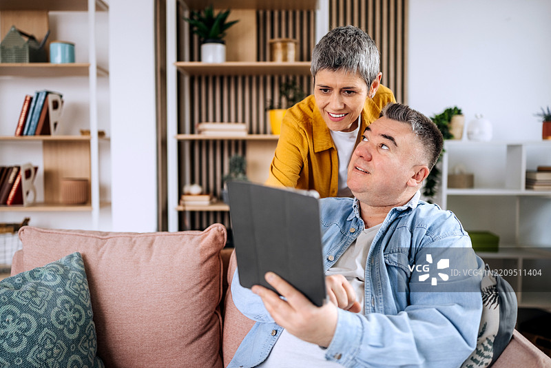 成熟男性与妻子在家中使用平板电脑图片素材