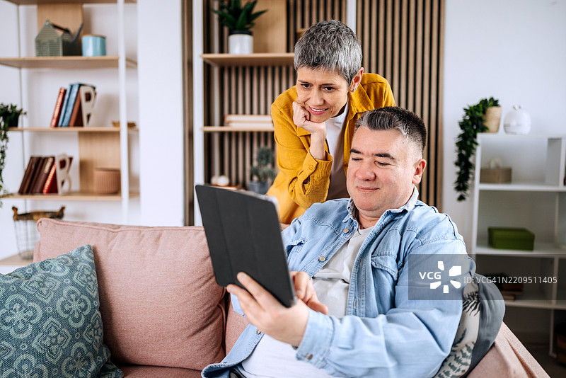成熟男性与妻子在家中使用平板电脑图片素材