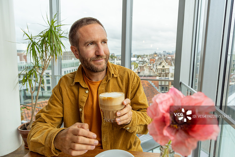 咖啡馆里的男人享受着城市景观和咖啡图片素材