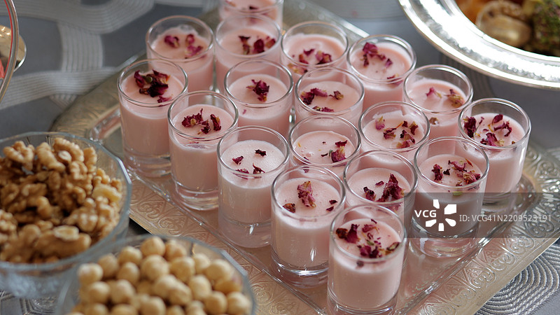 一个精美的甜品桌；马卡龙、小点心、三明治、粉色汉堡、糖果、饼干、杯子蛋糕。装饰华丽的新娘准备室桌子，甜品角落，婚礼糖果吧，糖果自助餐，婚礼上的美味糖果吧。图片素材