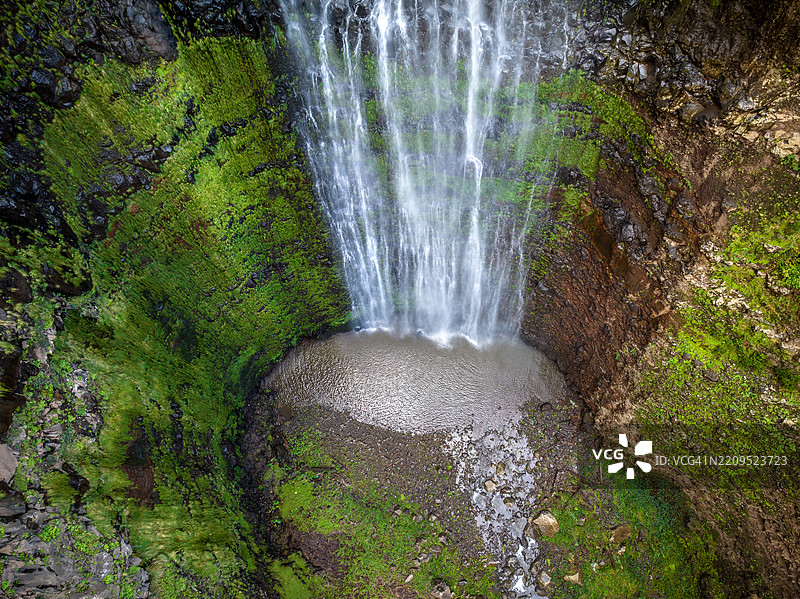 垂直瀑布倾泻而下，岩石地形环绕着壮观的加尔甘塔丰达瀑布，周围是郁郁葱葱的风景，位于葡萄牙的马德拉山区。图片素材