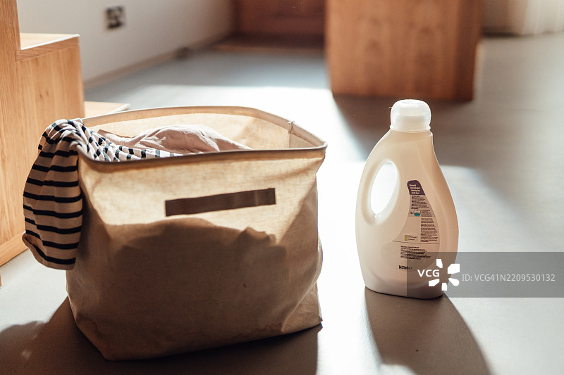 一个装满脏衣服的洗衣篮和一瓶液体洗涤剂图片素材