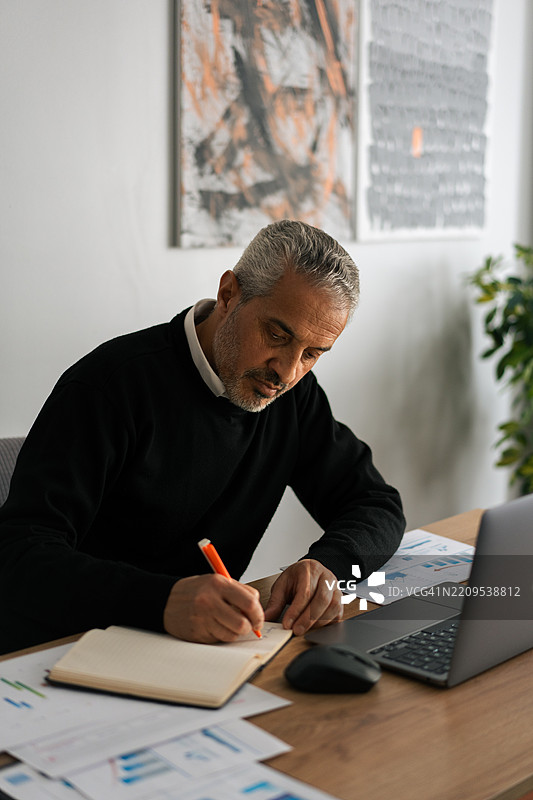 专注的成熟商人在现代办公室的桌子上工作图片素材