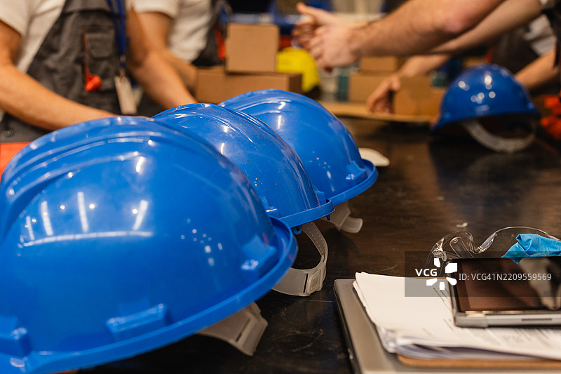 蓝色安全帽整齐地摆放在仓库或工业环境中的桌子上图片素材