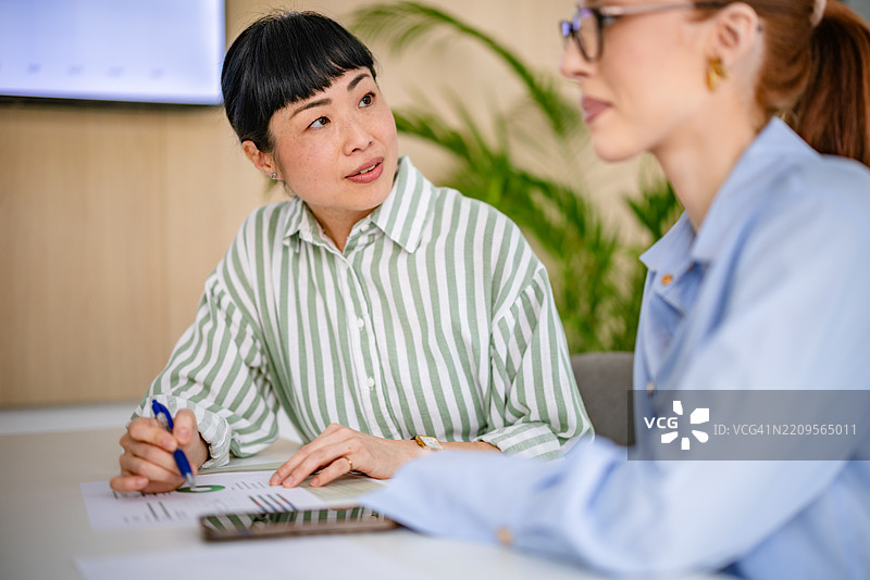 现代办公室中多元文化团队会议，专注于职业女性之间的合作与战略规划图片素材