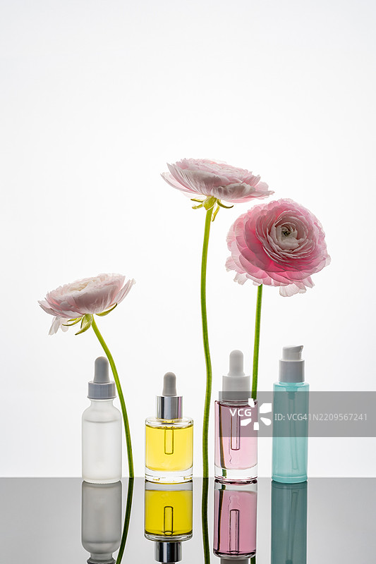 各种护肤瓶与粉色的毛茛花图片素材