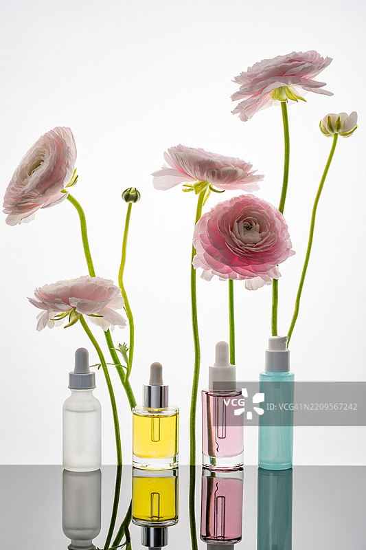 各种护肤瓶与粉色的毛茛花图片素材