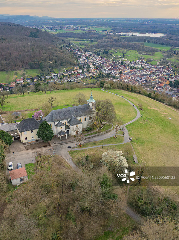 教堂坐落在山丘上，周围是春天的复苏，盛开的树木和宁静的小径，米歇尔斯贝格，巴德·明斯特赖费尔图片素材