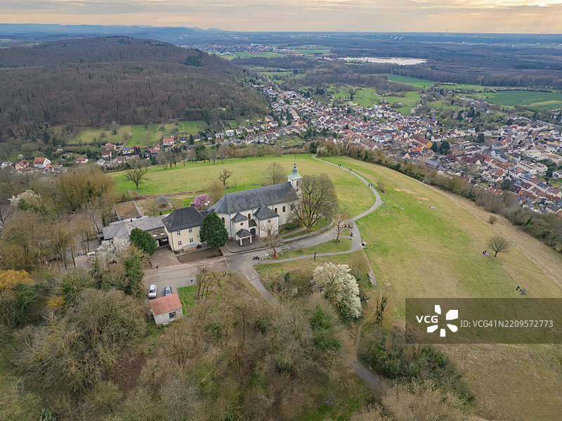 鸟瞰一座位于丘陵村庄中的教堂，四周环绕着树木，俯瞰广阔的风景，米歇尔斯贝格，巴德明斯特赖费尔图片素材
