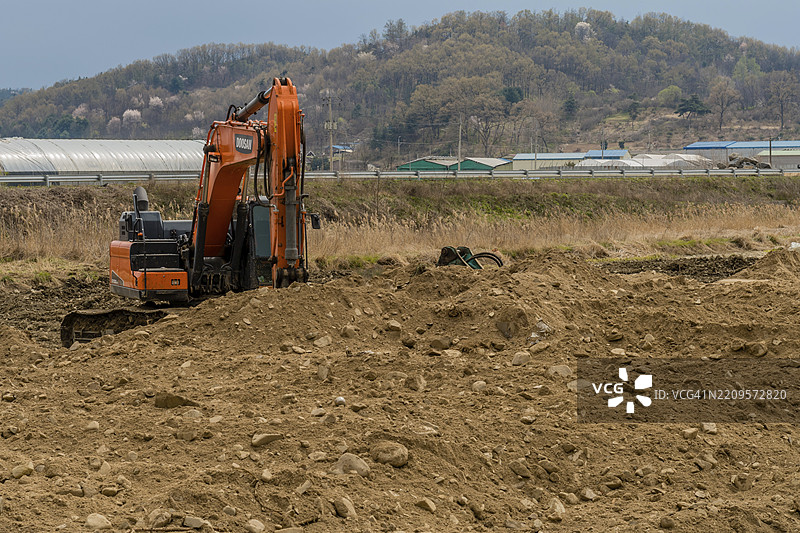 韩国大田。2020年4月12日：仅供编辑使用。橙色挖掘机静静地停在乡村施工现场图片素材