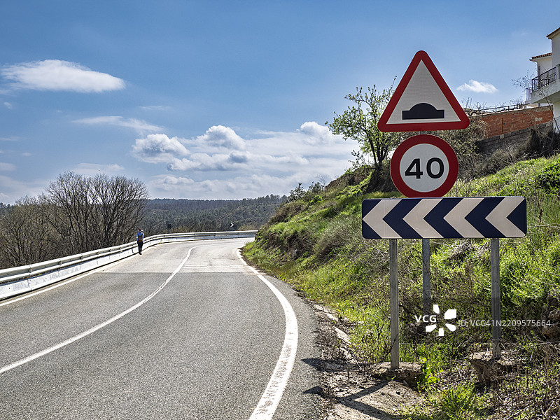 一名行人在道路的弯道上行走。图片素材