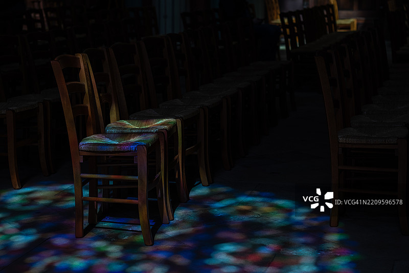 教堂内昏暗灯光下的椅子被彩色玻璃映衬图片素材