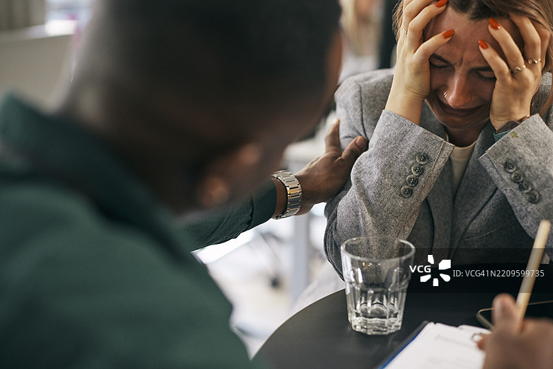 男性商务专业人士在办公室安慰情绪低落的女性同事图片素材