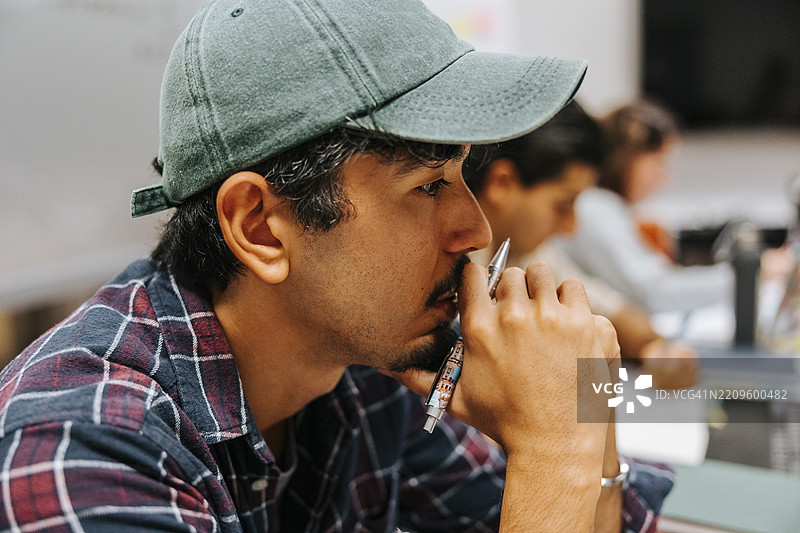 在大学教室里，戴着帽子的沉思男子图片素材