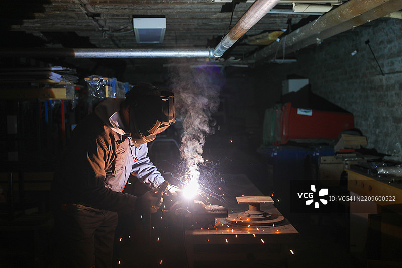 工业工人在昏暗的车间里焊接金属图片素材