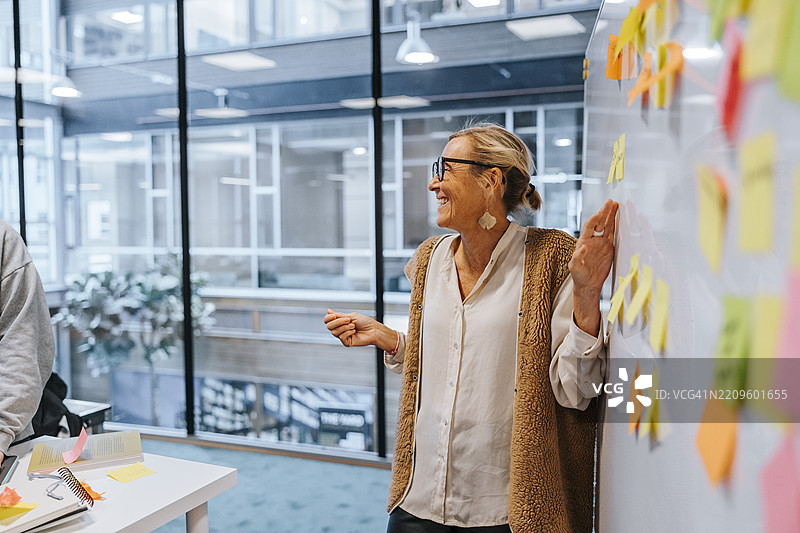 快乐的女性教师站在白板旁边，在科技大学授课图片素材