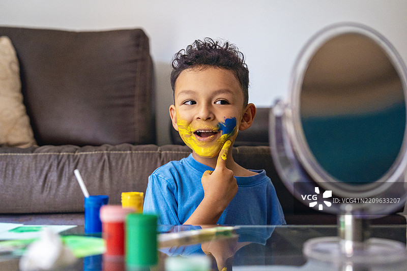 孩子在镜子前用刷子给自己画脸图片素材
