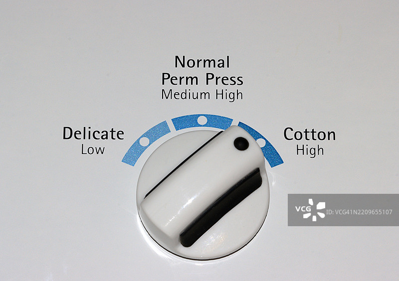白色顶装洗衣机上的控制旋钮，设置为棉织物模式图片素材