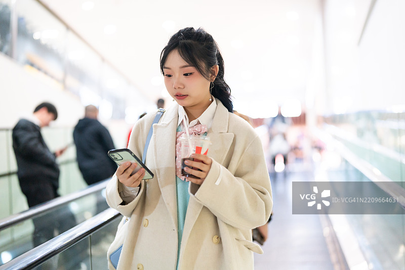 亚洲年轻女性在购物中心使用电子设备图片素材