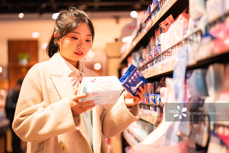 一位亚洲女性在超市购买卫生巾图片素材