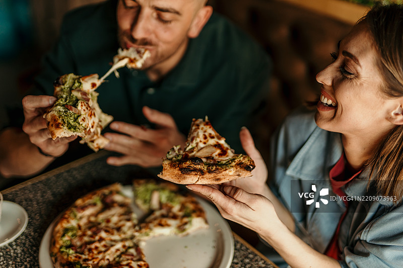 情侣在餐厅享用美味的比萨饼图片素材
